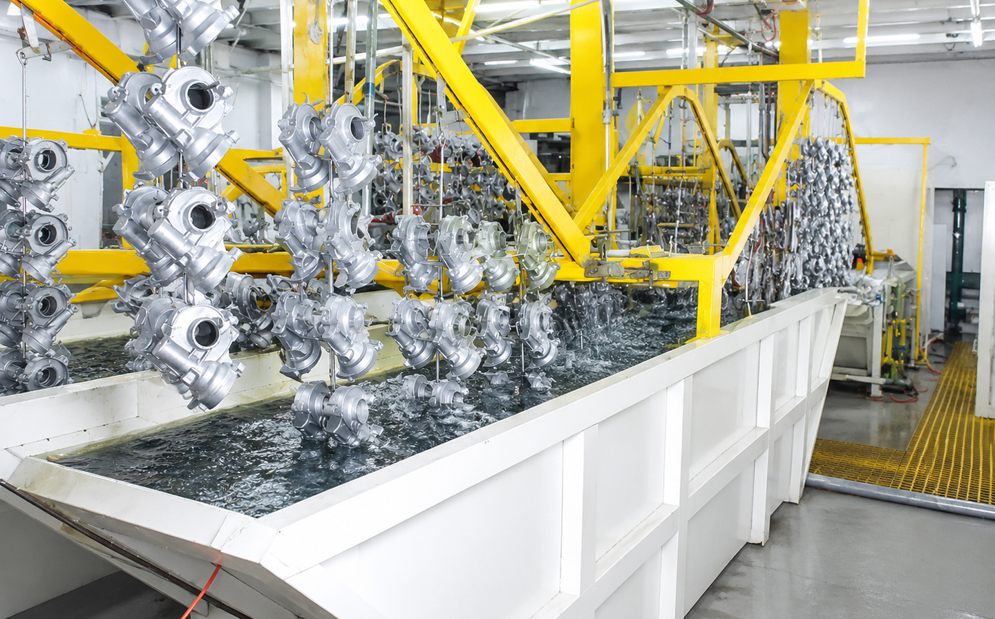 Línea-de-limpieza-por-inmersión-industrial-brillante-con-piezas-metálicas-suspendidas-sobre-un-tanque-de-limpieza-química-dentro-de-un-taller-de-fábrica-moderna